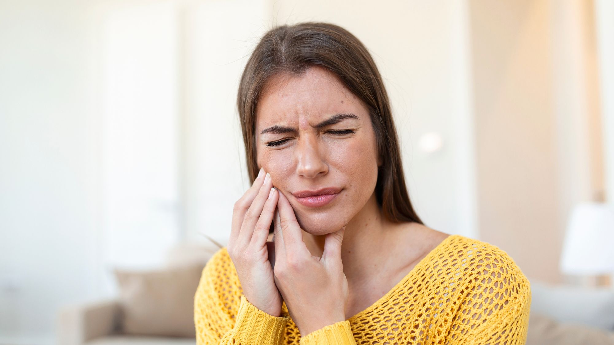 A girl holding her mouth, suffering from pain due to teeth sensitivity
