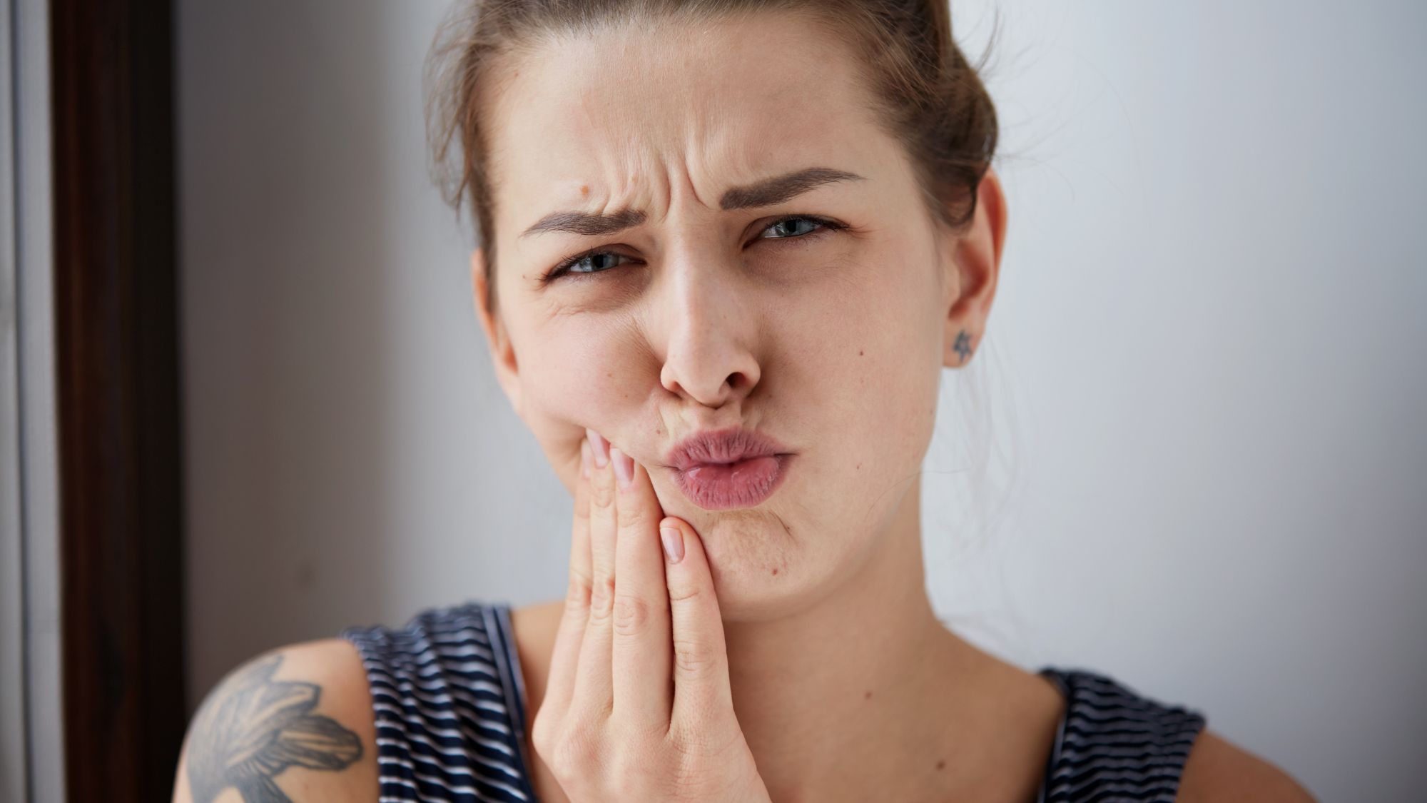 A woman covering her mouth in pain due to bleeding gums