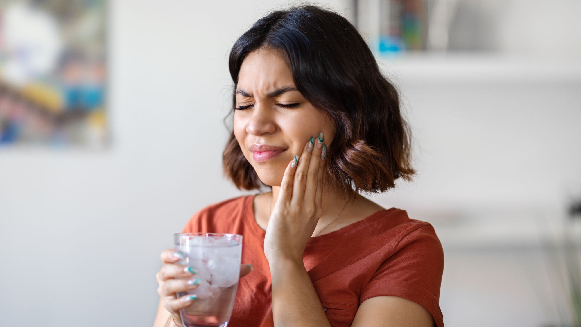 A woman holding her mouth due to teeth sensitivity after teeth whitening