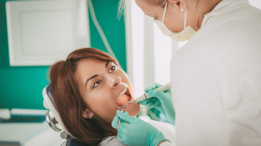 A woman is visiting a dentist for treatment of gum bleeding while brushing