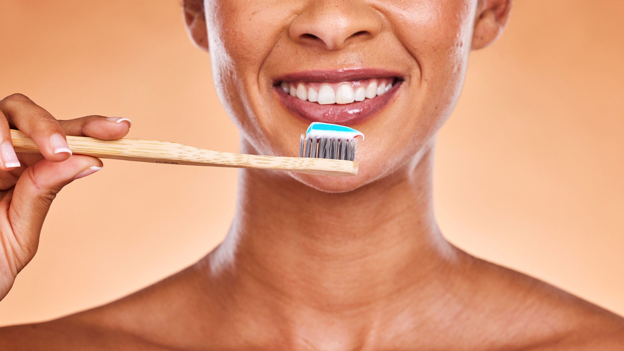 A woman smiling while holding a toothbrush to support healthy oral care
