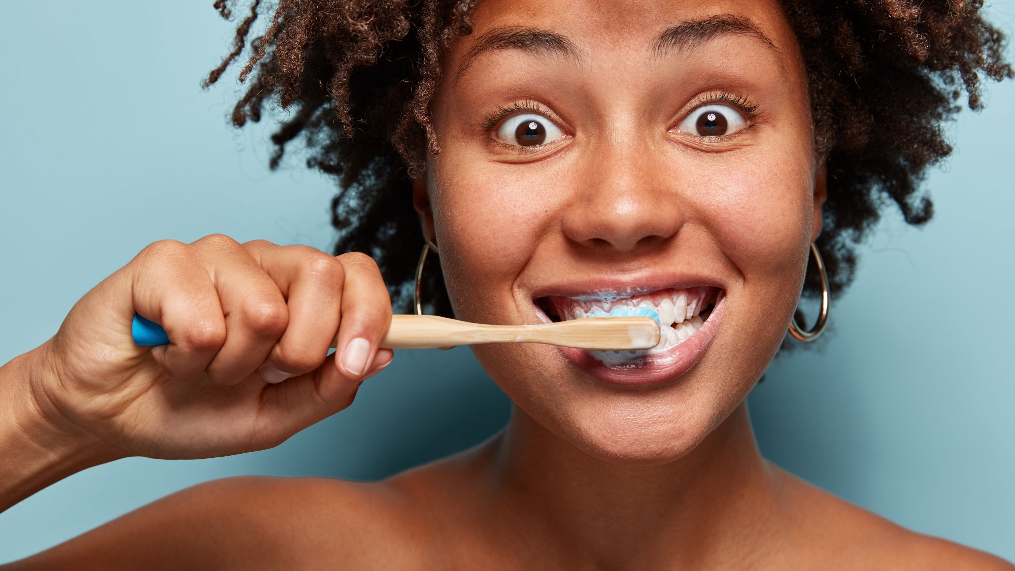 A young girl holding a toothbrush for healthier teeth, gums, and oral health