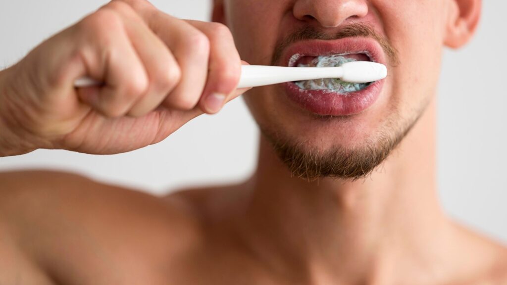 A boy smiling and holding a toothbrush to maintain good oral hygiene