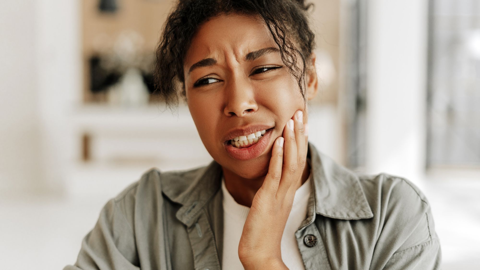 A black girl suffering from pain due to teeth sensitivity