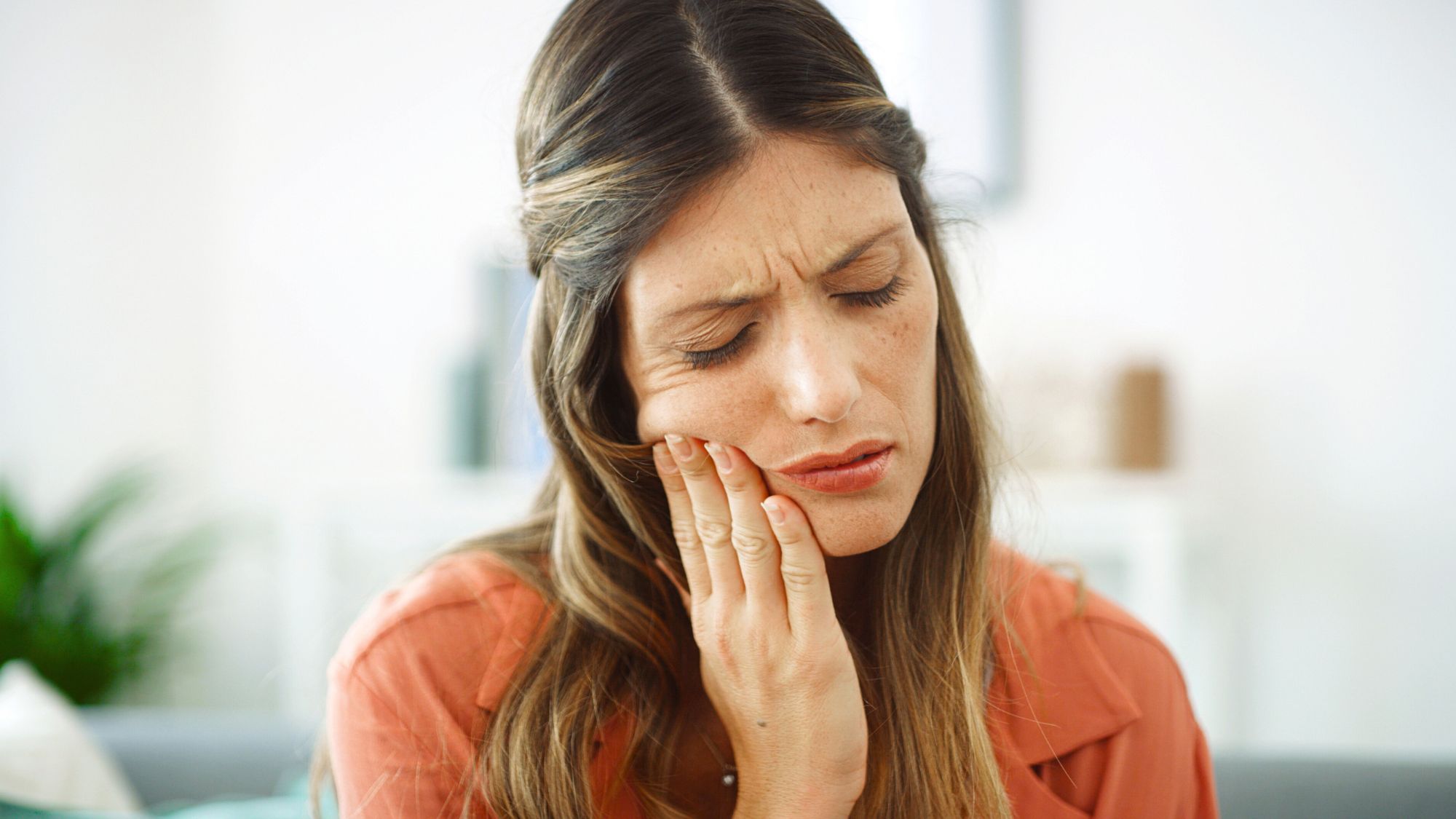 A woman holding her mouth due to severe teeth sensitivity pain