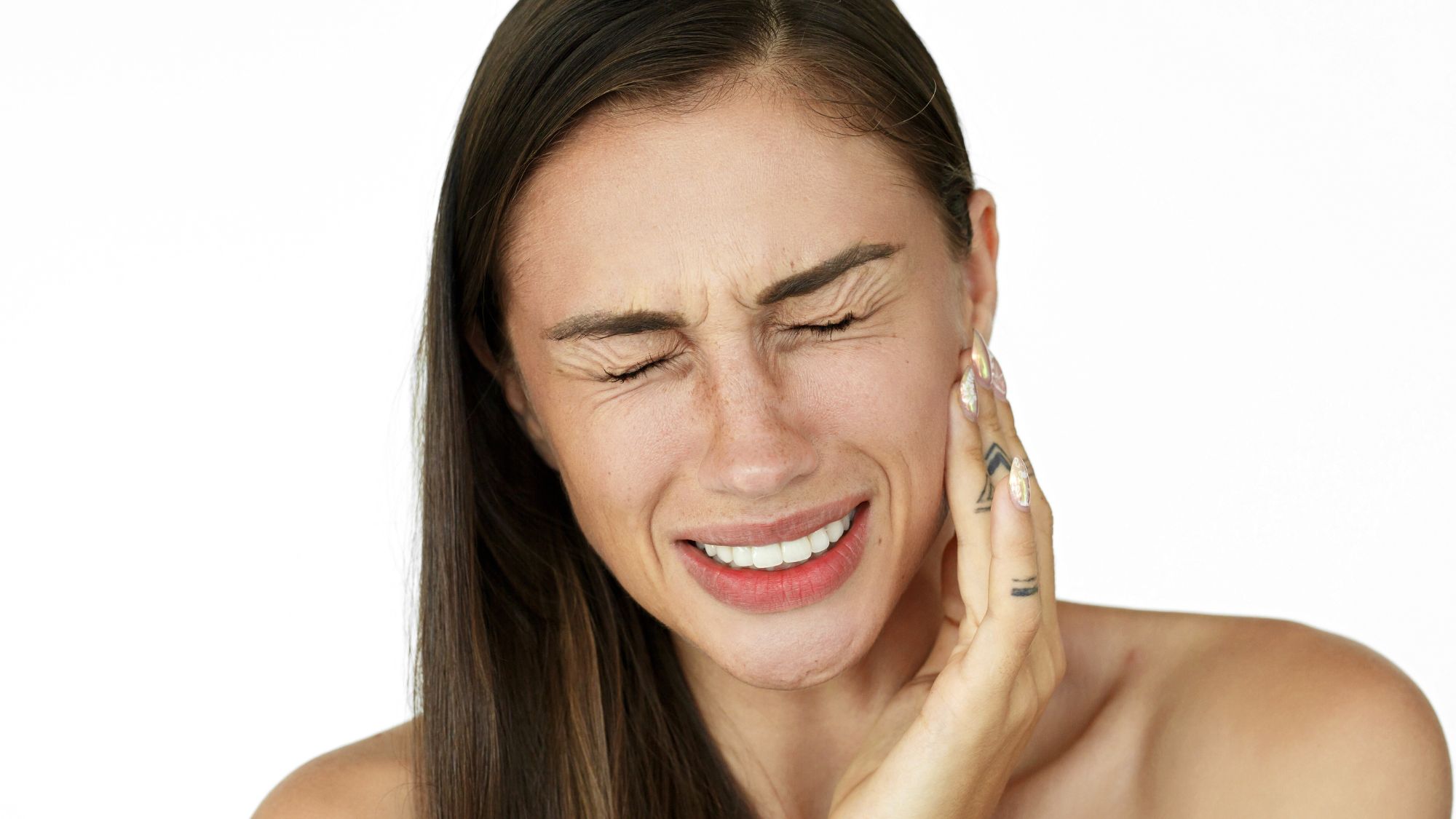 A woman holding her mouth due to tooth sensitivity pain